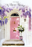 This doorway scene in Chesham feels like a softly spoken blessing for anyone starting a new chapter. A pale pink front door, painted in a warm, chalky blush, stands calm and inviting at the centre, its colour radiating against bright white walls that catch the gentle daylight often found on quiet roads leading away from Lowndes Park. Above, cascades of wisteria tumble in lavender and lilac tones, their drooping clusters forming a natural garland over the entrance, as if nature itself were decorating the home. The flowering vine's leafy stems weave along the top of the frame, creating dappled shade and hinting at a light floral fragrance drifting along the path. At the threshold, a sturdy grey metal florist's bucket rests neatly on the step, overflowing with generous white and cream roses mixed with soft green foliage. Each rose head is fully open and plush, petals curling outward in silky layers that catch subtle shadows. A delicate pink ribbon circles the bucket, tied in a loose bow that mirrors the door's pastel hue and adds a graceful, celebratory touch. The overall atmosphere is gentle yet quietly uplifting, suggesting the moment a family or couple first arrives at their new home with a housewarming gift arranged by a local Chesham florist. It feels like a bouquet meant to say welcome without words-ideal for congratulating someone on a move, offering comfort and good wishes, and bringing the soft beauty of roses and wisteria right to their doorstep, where every glance at the flowers and colour will remind them that this new space is truly theirs.